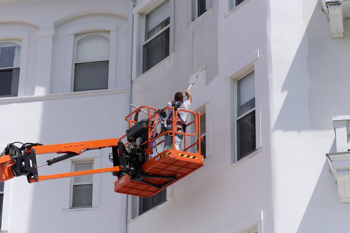 Carroll, NH USA - Painting the Omni Mt Washington Hotel. A man on a boom lift uses a roller to apply white paint to the facade of the building